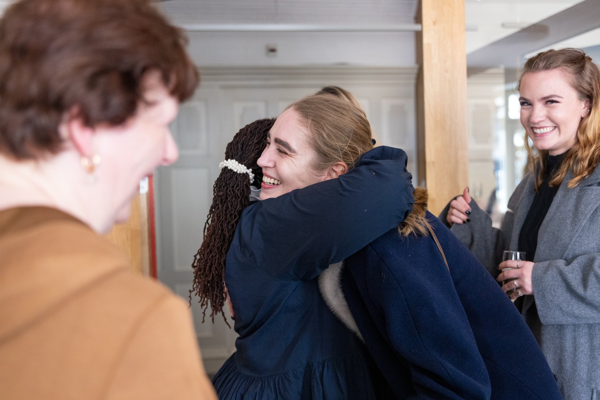 Two women hugging Two women in blue outfits hugging happily with a few other women nearby