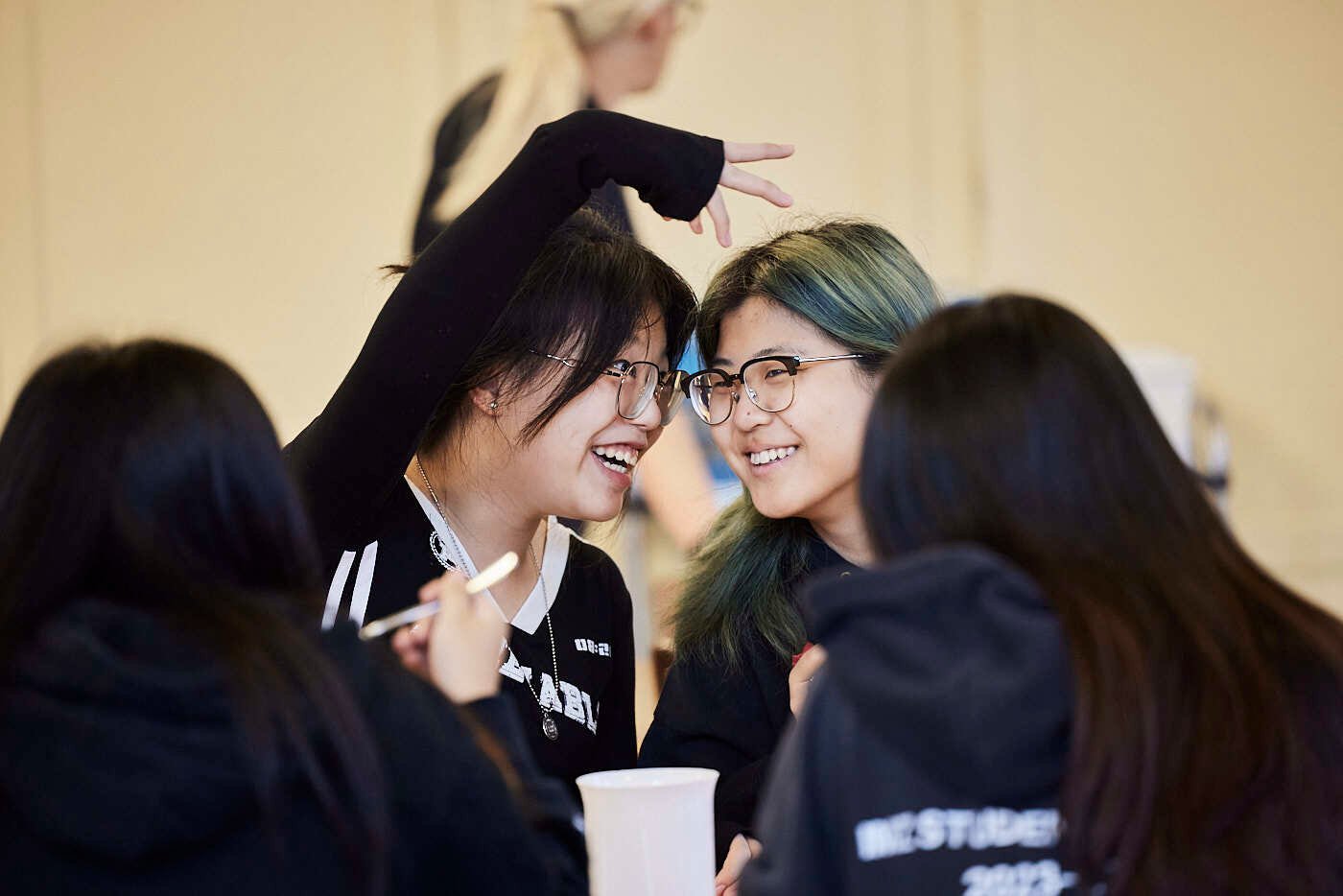 Two female students talking and laughing in a dining hall.