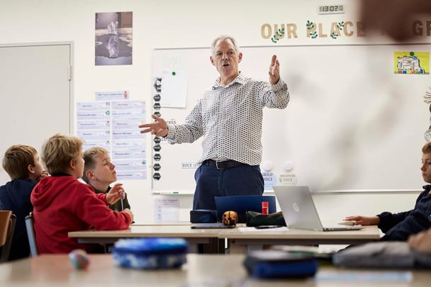 A teacher in white speaks to students.