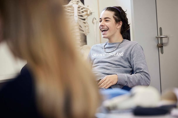 A girl student in a class laughs in a middle of discussion.