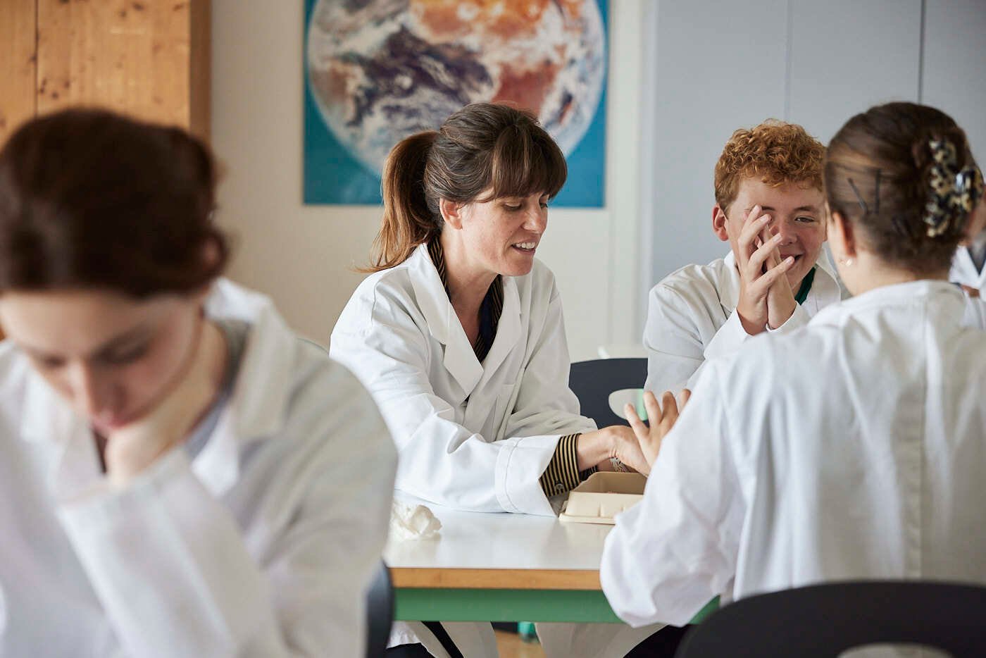 A female teacher and her other students are in a discussion in a lab.