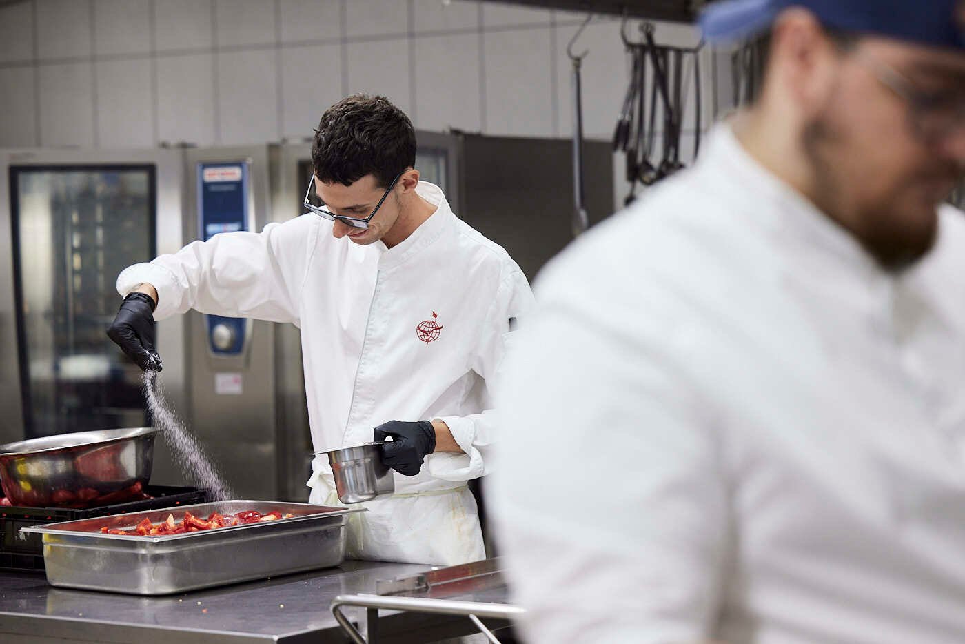 A male kitchen staff preparing something in a kitchen.