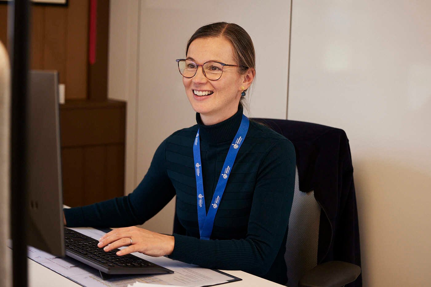 A female staff member work with her computer and smile.