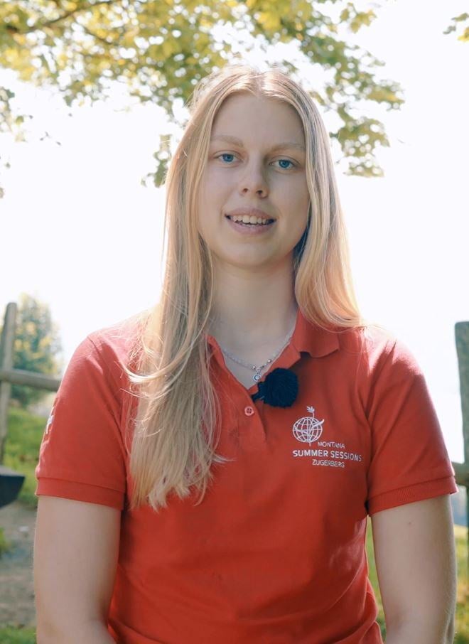 A young female mentor with blond long hair talks to camera in an outdoor setting.