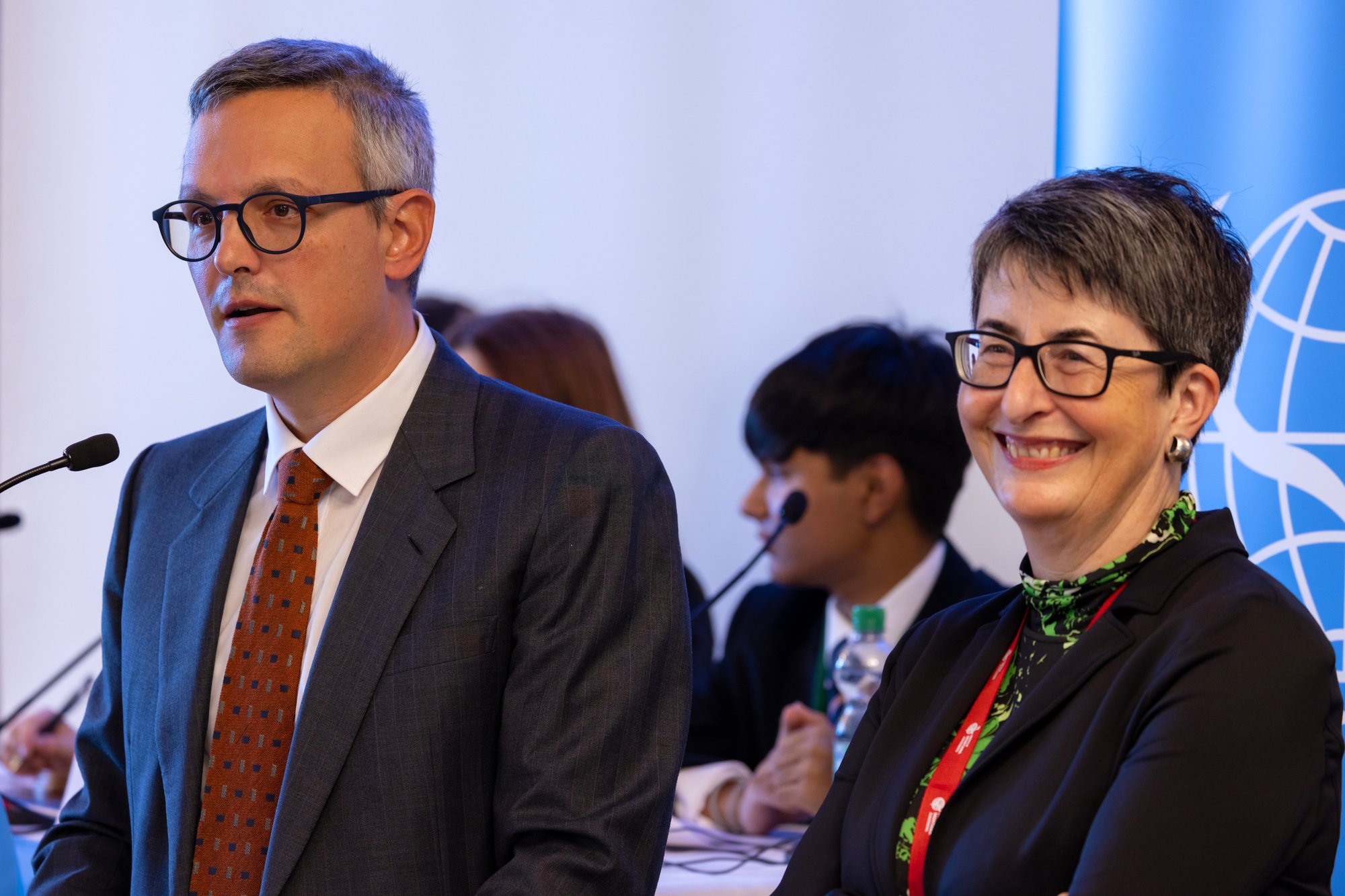 A man and a woman give a speech at a model united nations conference.