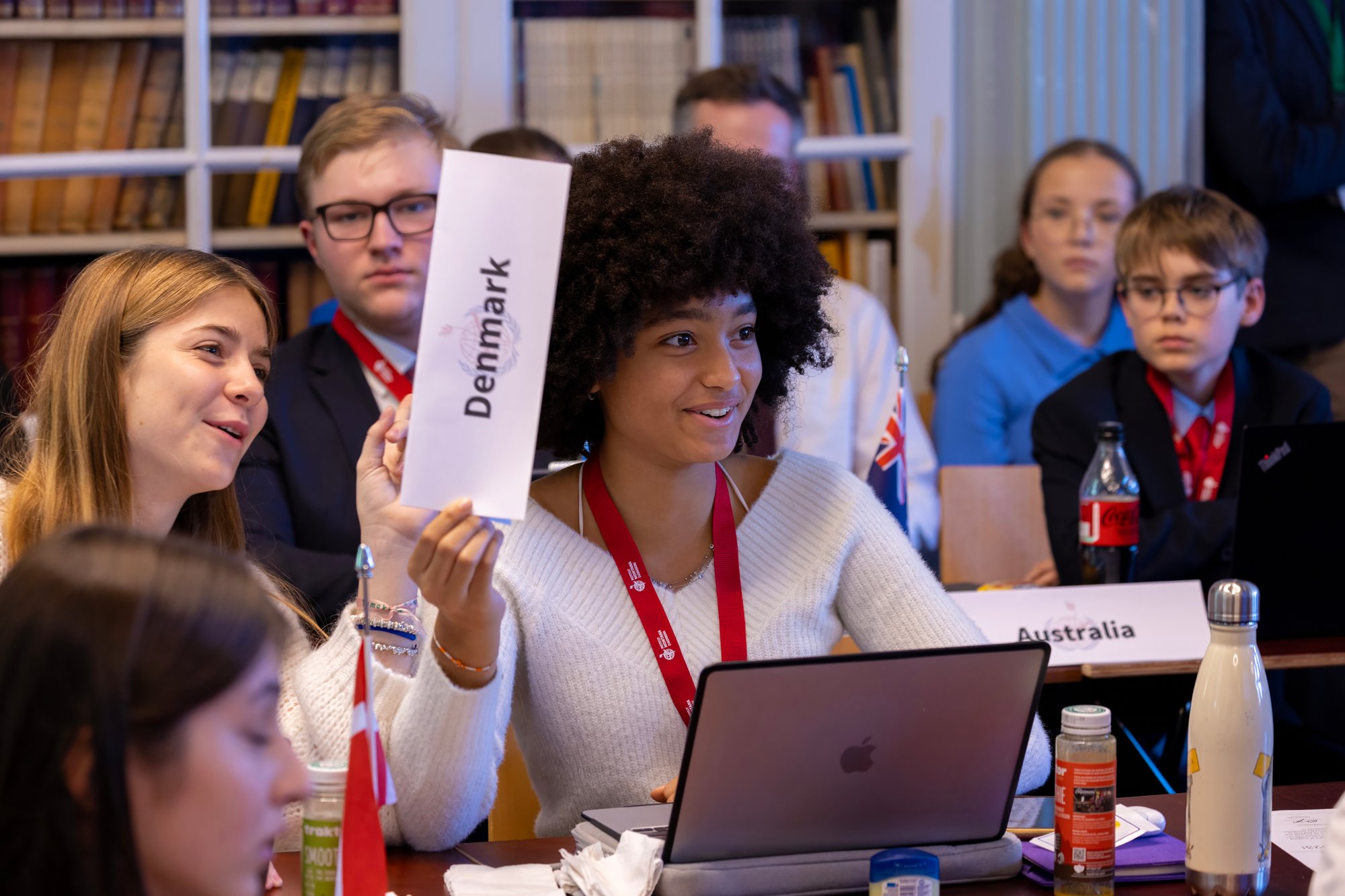 A female student participant at a conference lifts up her sign to talk.