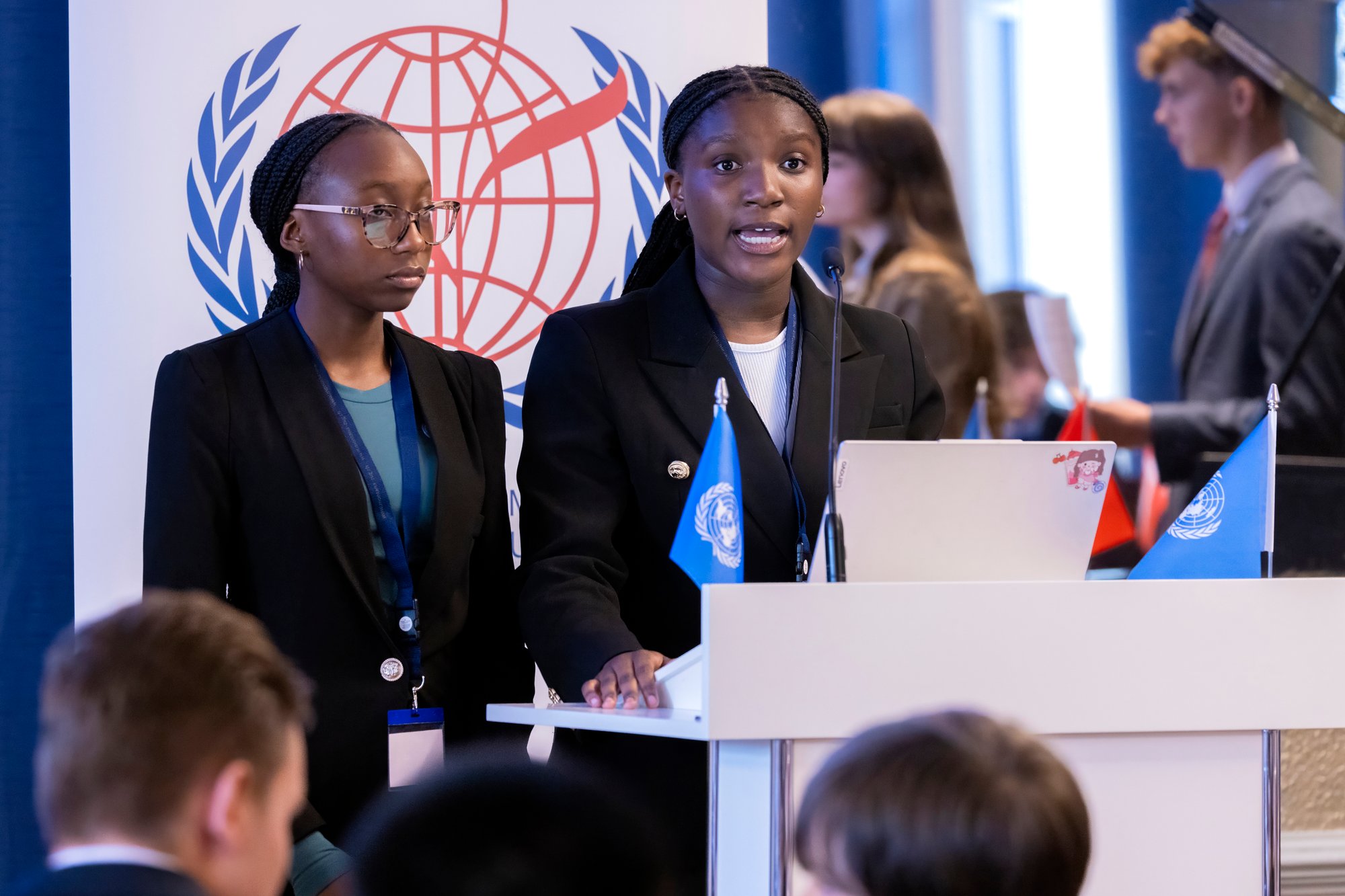 Two female students speak at a podium of model united nations conference.