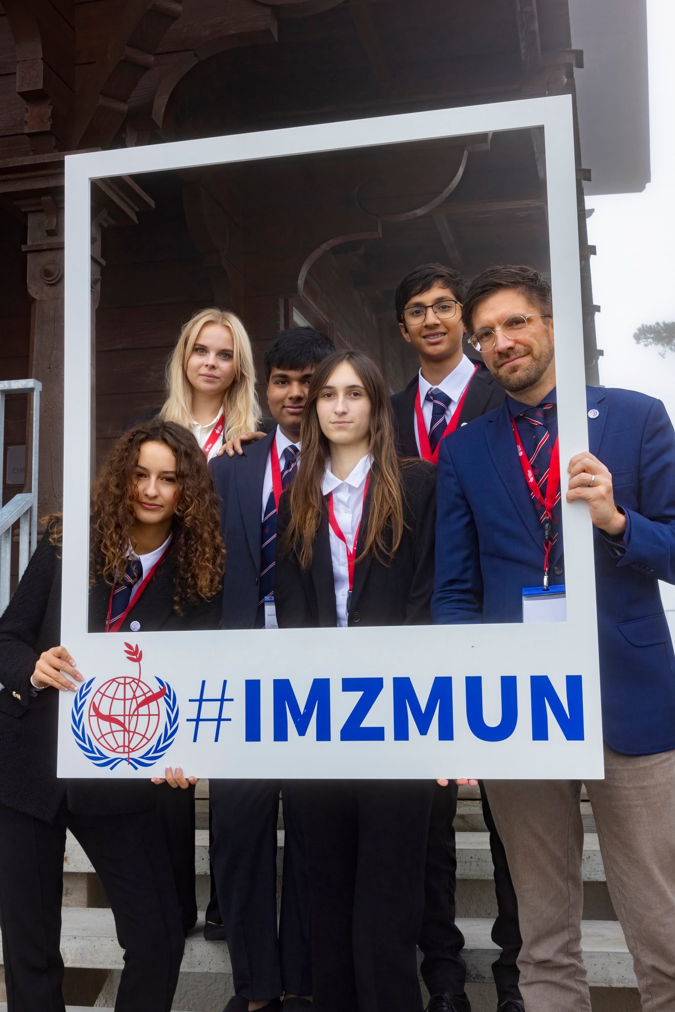 Five students with a male teacher pose on a stair.