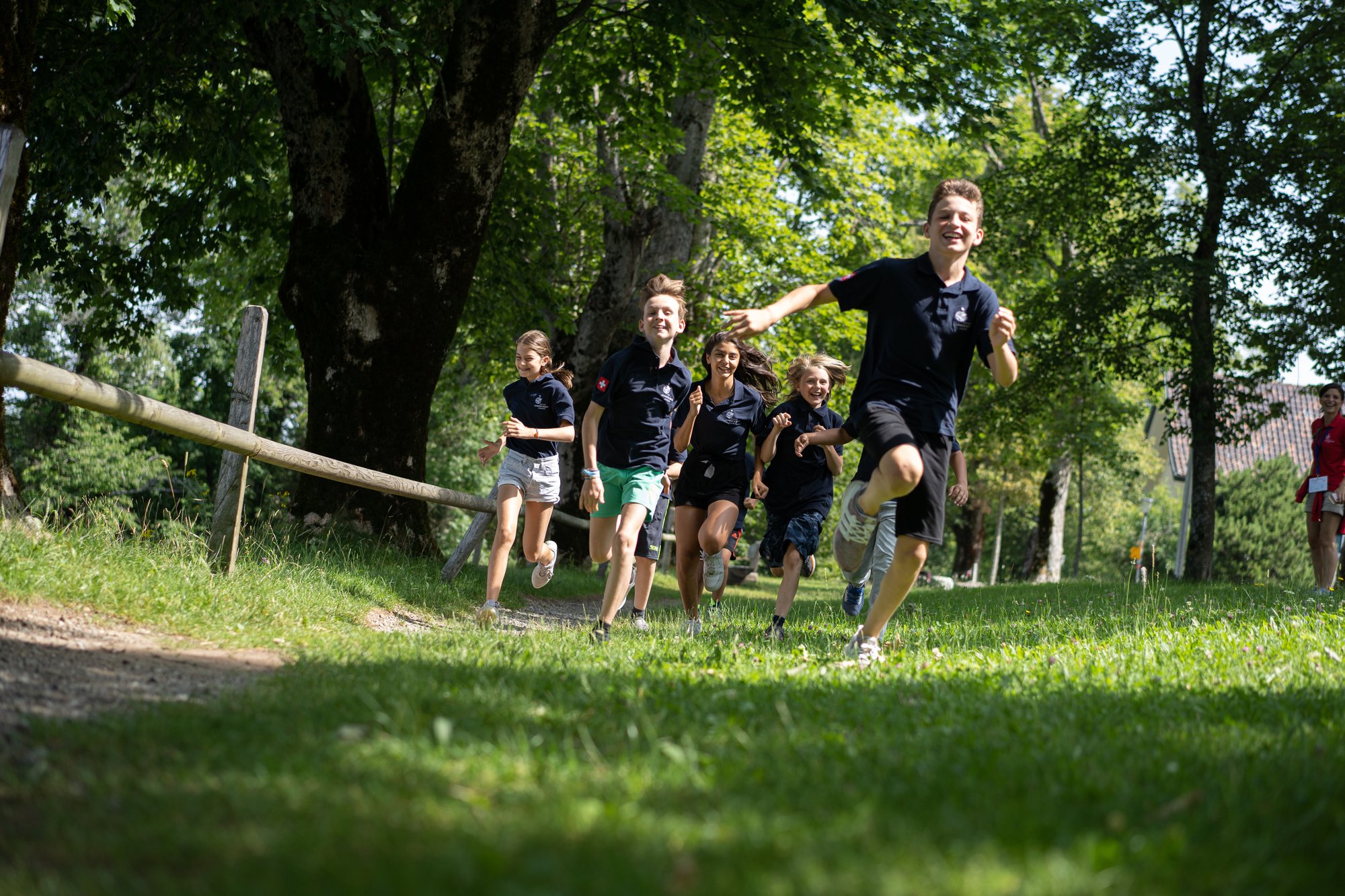 Boy and girl students running happily on a field on a sunny day.