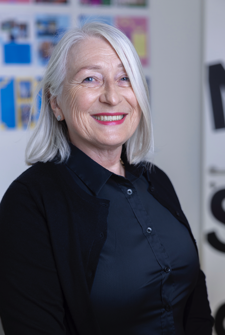 Grey-haired senior female teacher smile at the camera.