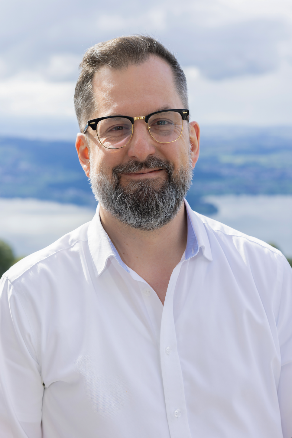 A male teacher with beard and glasses smile at camera.