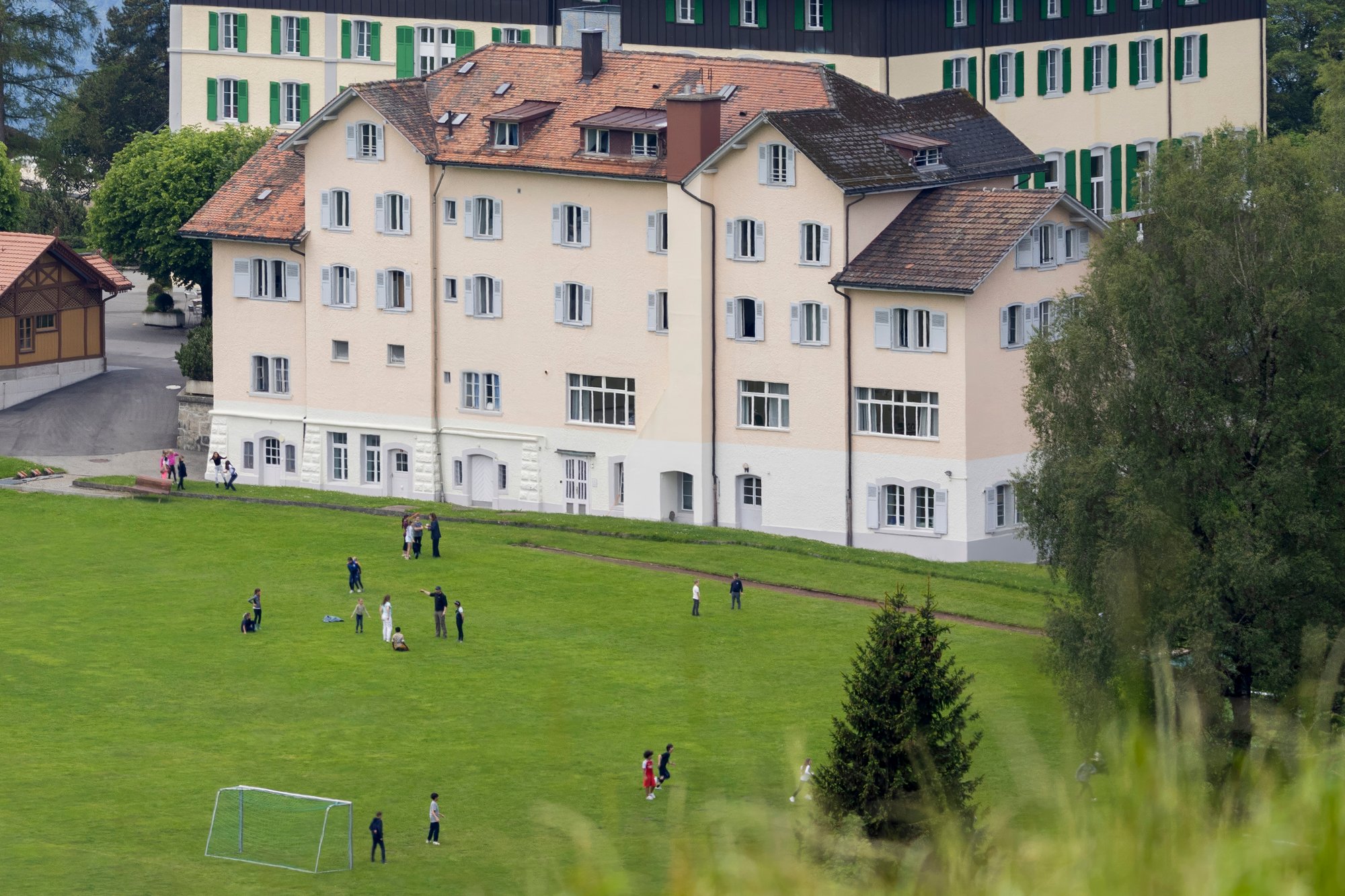 A light-painted building with children playing football outside.