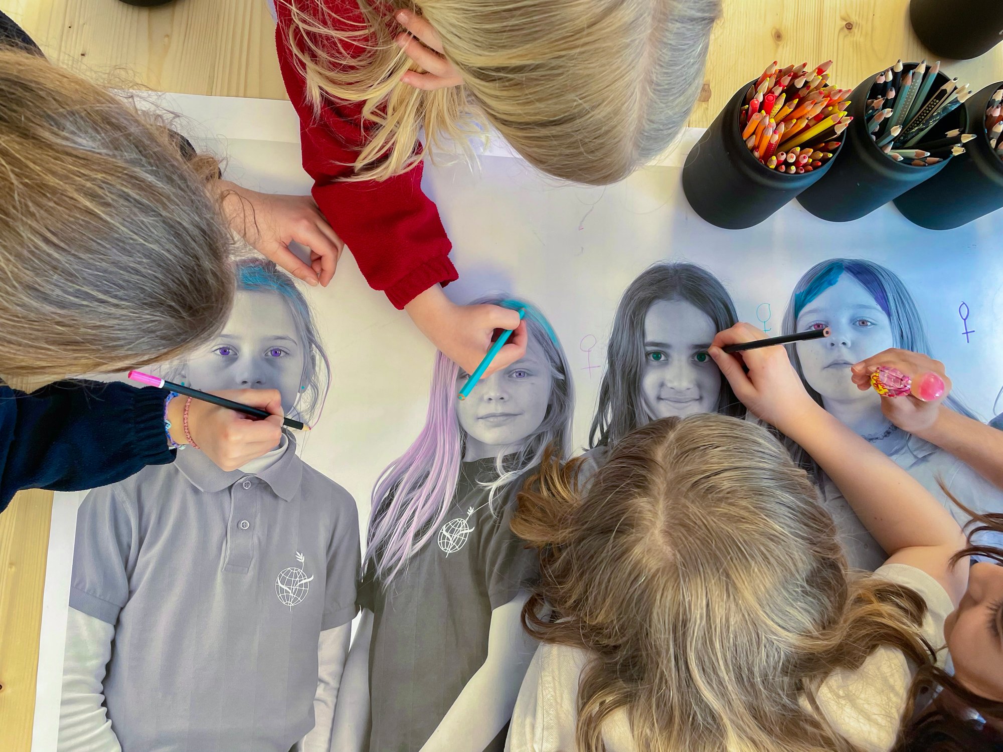 A couple of students draw together on a canvas.