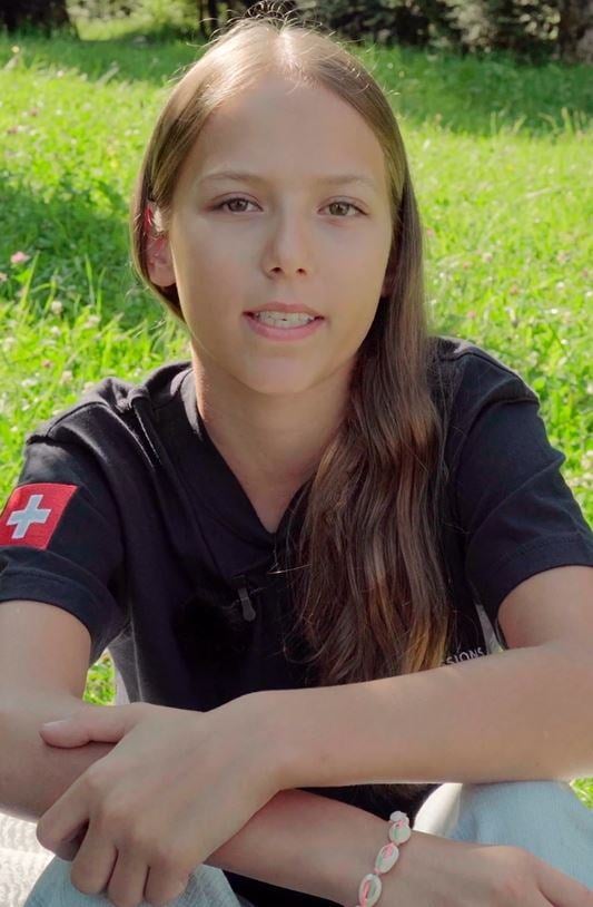 A girl student sits on a grass and talks to camera