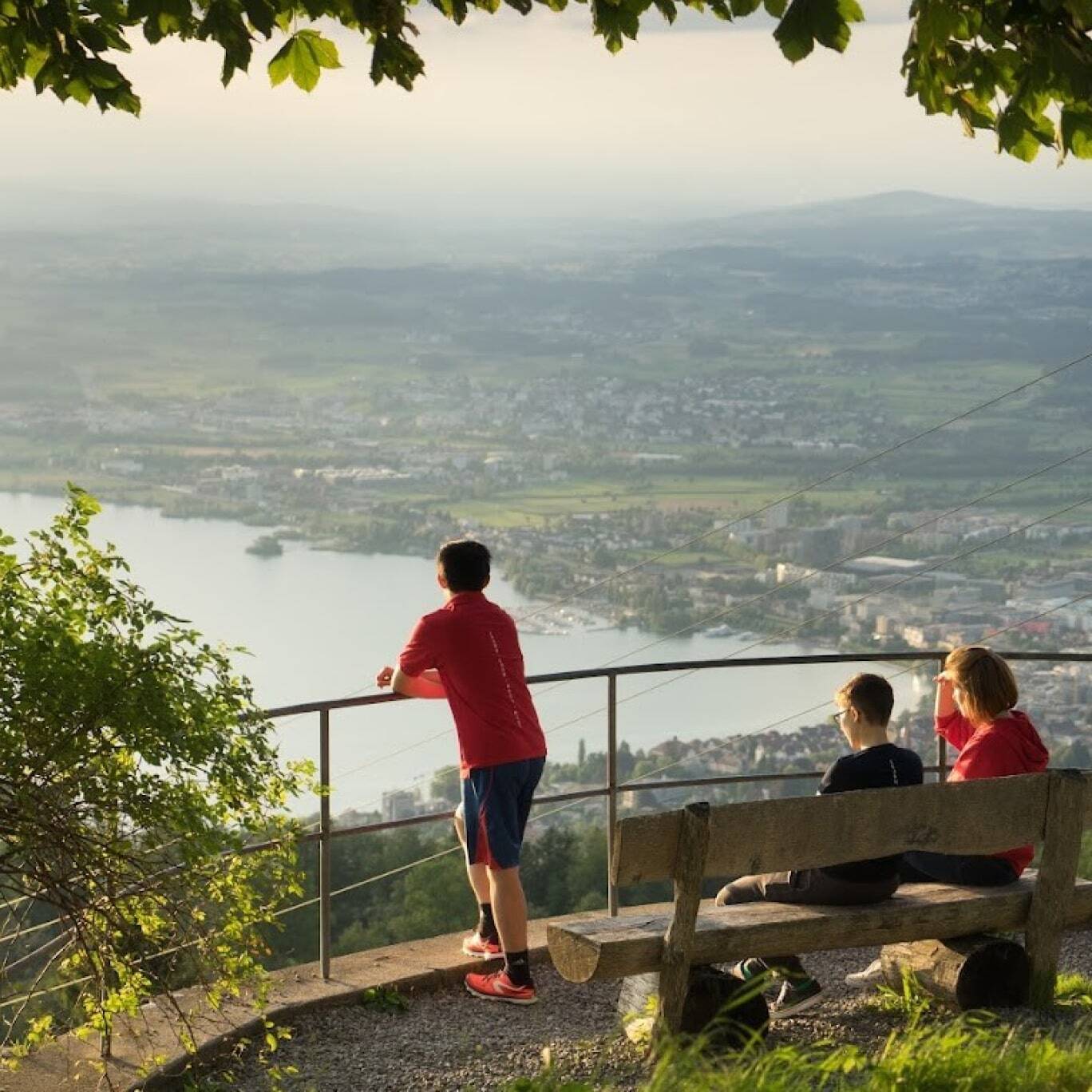 ine Gruppe von Menschen genießt an einem sonnigen Tag die Aussicht auf den Zugersee.