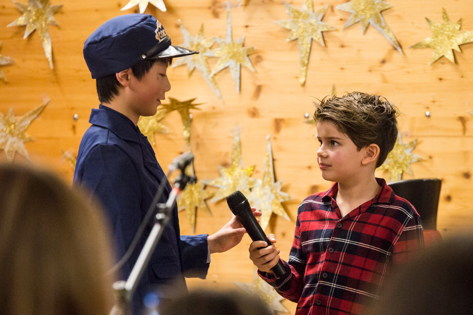 Two boy students in costumes perform a play in a room.