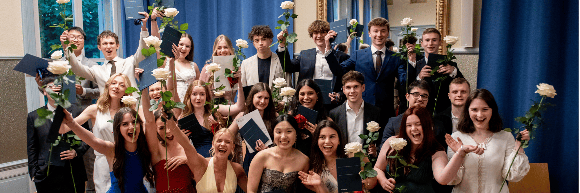 A group of students posing on their graduation day with white roses in hand.