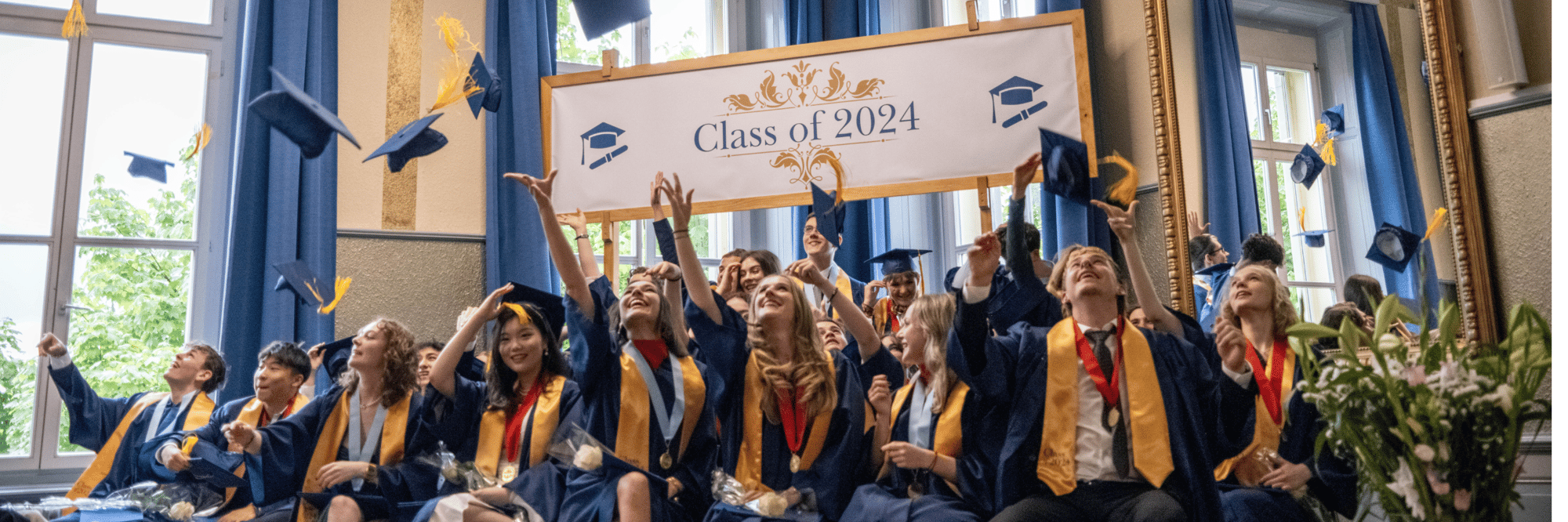 A group of male and female students dressed in their graduation outfits throw away their graduation caps.