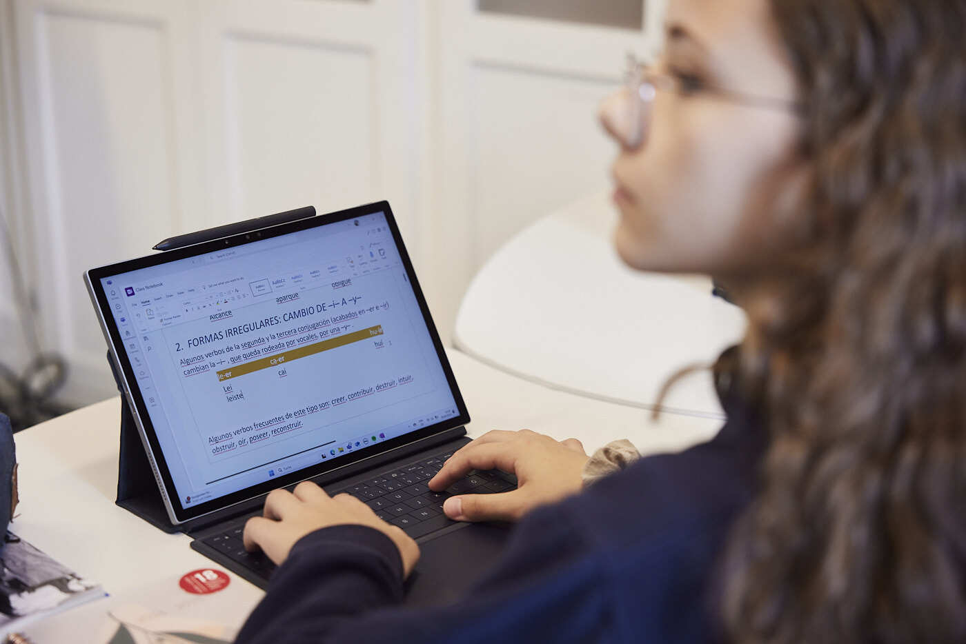 A female students on a chair, with a laptop in front of her, she looks another way.