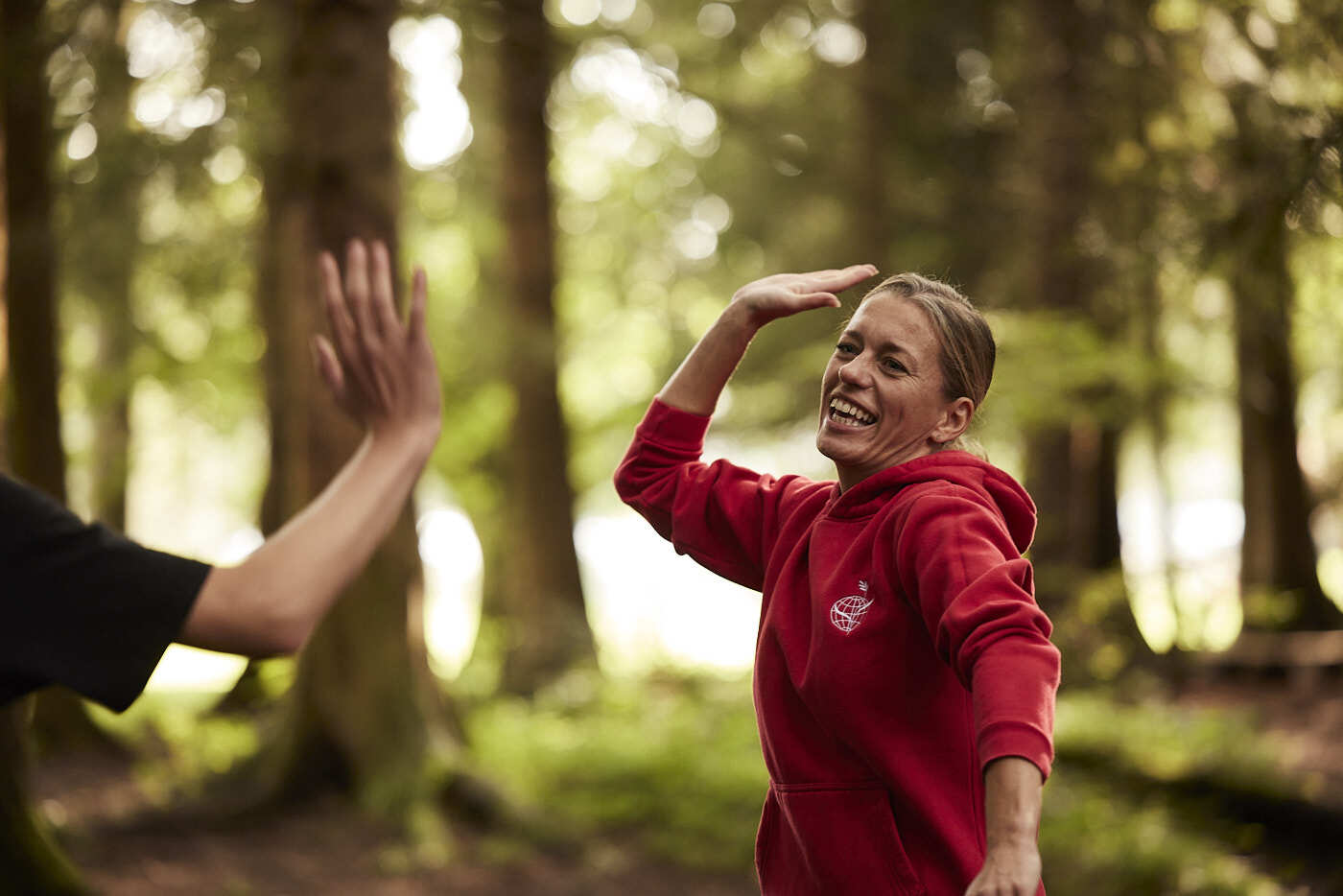 A woman in red top gives a high-five to a boy.